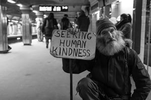 Homeless man with sign saying 'Seeking Human Kindness'