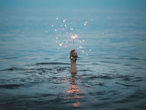 Hand in water holding a sparkler